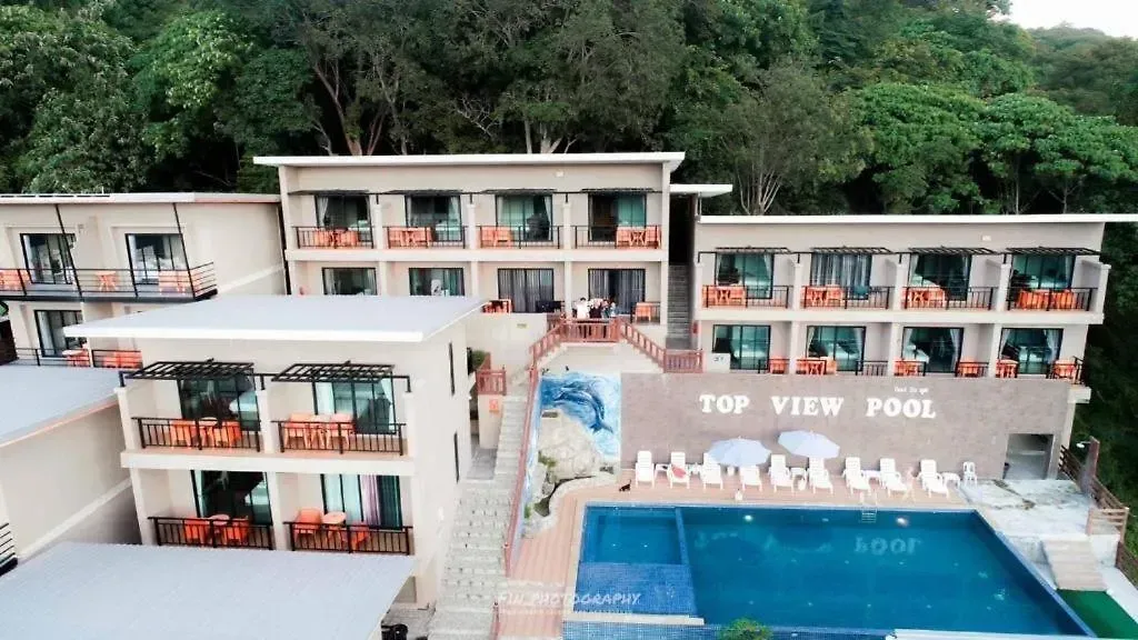 Front view of the white resort buildings with the swimming pool and cliff backdrop